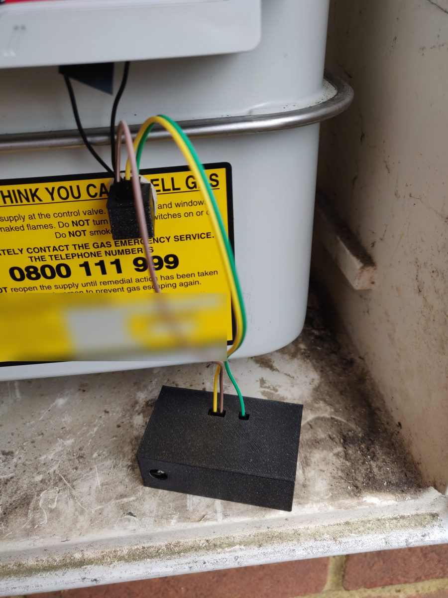 The gas meter unit in place: the reed switch housing is stuck to the meter just under the dial, and wired down to the case sitting in the bottom of the meter box.